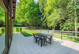 Terrazza esterna con tavolo e sedie, circondata da foresta presso il lodge Manonfa in Belgio.