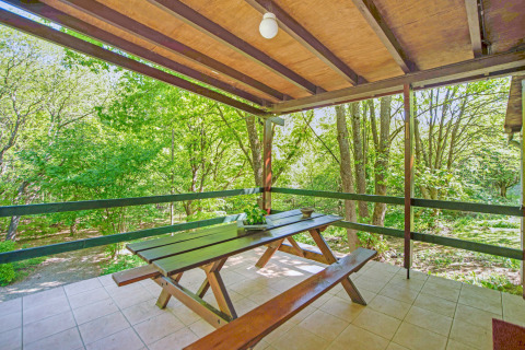 Terrazza coperta alla lodge Manonfa con tavolo da picnic, immersa nel verde in Belgio.