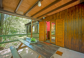 Veranda in legno con panca e vista sul bosco all’ingresso del lodge Manonfa in Belgio.