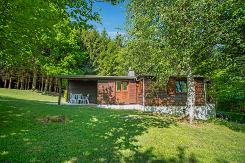 Foto del lodge Manonfa in Belgio, immerso nel verde, circondato da boschi e prato sotto il cielo azzurro.