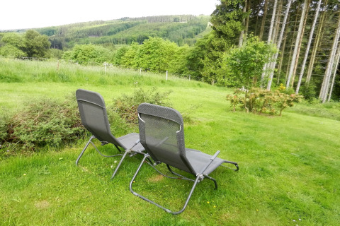 To liggestole på en græsplæne med udsigt over grønne bakker og skove ved Le Chaly-chalet i Belgien.