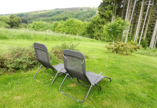To liggestole på en græsplæne med udsigt over grønne bakker og skove ved Le Chaly-chalet i Belgien.