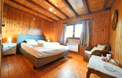 Acogedor dormitorio con paredes de madera, cama doble y ventana en el chalet 'HORTENSIAS' en Bélgica.