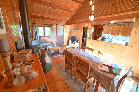 Interieur van chalet 'HORTENSIAS' in België, met houten muren, eettafel en gezellige woonkamer.