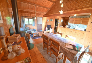 Interieur van chalet 'HORTENSIAS' in België, met houten muren, eettafel en gezellige woonkamer.