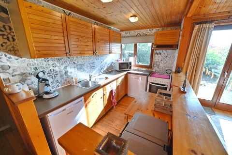 Gezellige houten keuken met betegelde wand in chalet HORTENSIAS in België, lichte ruimtes en tuinaanzicht.