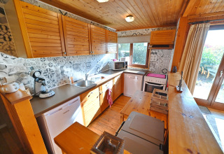 Gezellige houten keuken met betegelde wand in chalet HORTENSIAS in België, lichte ruimtes en tuinaanzicht.