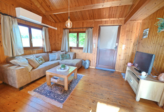 Gezellige woonkamer in chalet HORTENSIAS in België met houten inrichting, bank en televisie.