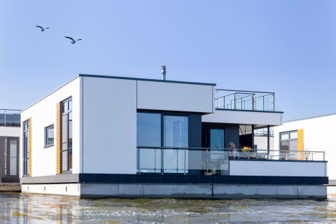 Casa galleggiante moderna con ringhiere in vetro sull'acqua a Ribnitz-Damgarten, Germania.