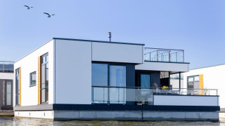 Casa galleggiante moderna con ringhiere in vetro sull'acqua a Ribnitz-Damgarten, Germania.