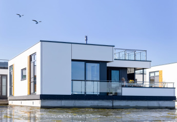 Casa galleggiante moderna con ringhiere in vetro sull'acqua a Ribnitz-Damgarten, Germania.