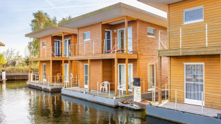 Moderne schwimmende Hausboote am Wasser, Holzbauweise, Platz für sechs Personen, mit Terrasse.