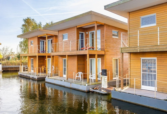 Case galleggianti moderne in legno, attraccate sull’acqua, dotate di terrazze per sei persone.