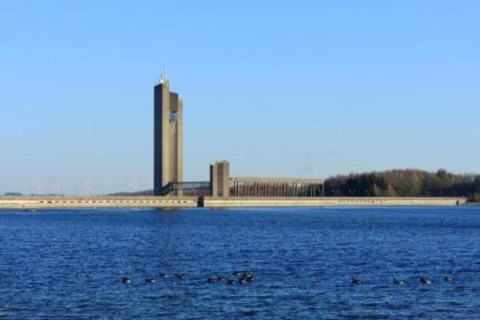 Uitzicht op een hoge moderne toren aan het water vanuit chalet Hortensias in België bij helder weer.