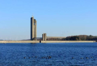 Uitzicht op een hoge moderne toren aan het water vanuit chalet Hortensias in België bij helder weer.
