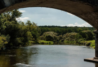 Uitzicht op een rustige rivier omgeven door groen, gezien onder een brug bij chalet HORTENSIAS in België.