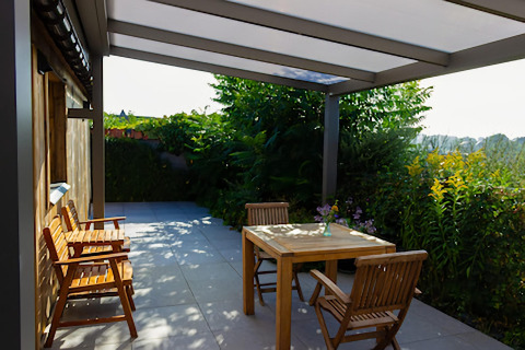 Terrasse extérieure du lodge Le Chalet de Bioul en Belgique, avec meubles en bois et verdure luxuriante.