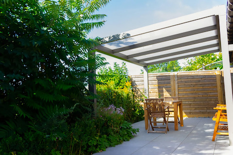 Terrasse extérieure au Chalet de Bioul en Belgique avec meubles en bois, pergola et végétation luxuriante.