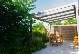 Terrasse extérieure au Chalet de Bioul en Belgique avec meubles en bois, pergola et végétation luxuriante.