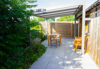 Terrasse extérieure du Chalet de Bioul en Belgique avec salon de jardin en bois et verdure luxuriante.