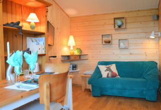 Chalet en bois chaleureux avec canapé bleu, table à manger et déco au Chalet de Bioul, Belgique.