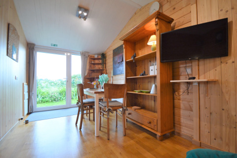 Intérieur lumineux et chaleureux du Chalet de Bioul en Belgique, murs en bois, table à manger et vue sur le jardin.