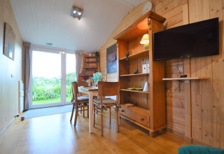 Intérieur lumineux et chaleureux du Chalet de Bioul en Belgique, murs en bois, table à manger et vue sur le jardin.