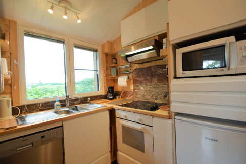 Cuisine moderne avec grande fenêtre, évier, four, micro-ondes et frigo au Chalet de Bioul en Belgique.