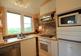 Cuisine moderne avec grande fenêtre, évier, four, micro-ondes et frigo au Chalet de Bioul en Belgique.