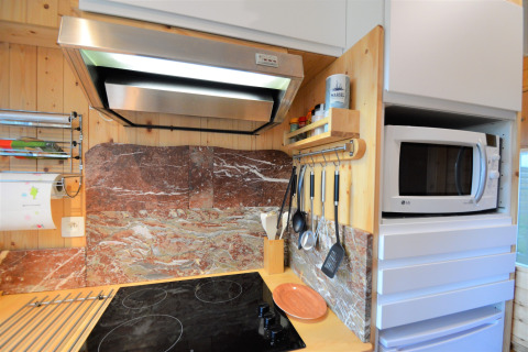 Coin cuisine moderne au Chalet de Bioul, Belgique, avec plaque, hotte, ustensiles et micro-ondes.