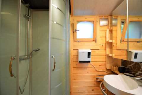 Salle de bain moderne au Chalet de Bioul en Belgique, avec murs en bois, douche et lavabo.