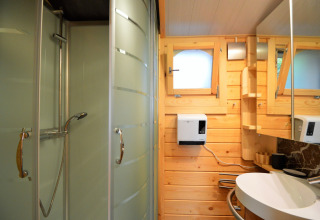 Salle de bain moderne au Chalet de Bioul en Belgique, avec murs en bois, douche et lavabo.