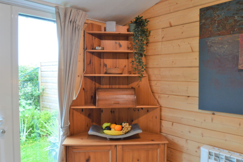 Étagère d’angle en bois avec plateau de fruits et plante suspendue dans Le Chalet de Bioul, Belgique.