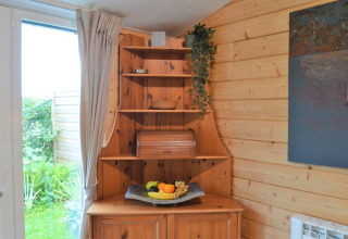 Étagère d’angle en bois avec plateau de fruits et plante suspendue dans Le Chalet de Bioul, Belgique.