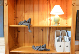 Étagère en bois avec lampe, deux sculptures de personnages allongés et range-documents au Chalet de Bioul.