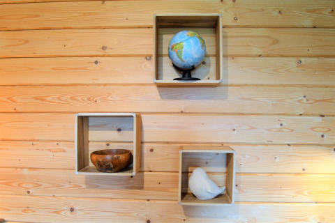 Trois caisses en bois sur un mur à Le Chalet de Bioul, Belgique, avec un globe, bol et statue d’oiseau blanc.