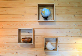 Trois caisses en bois sur un mur à Le Chalet de Bioul, Belgique, avec un globe, bol et statue d’oiseau blanc.
