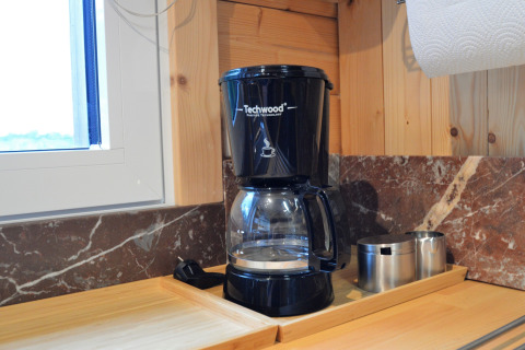 Cafetière Techwood sur un plan de travail en bois au Chalet de Bioul, Belgique, avec tasses métalliques.