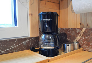 Cafetière Techwood sur un plan de travail en bois au Chalet de Bioul, Belgique, avec tasses métalliques.