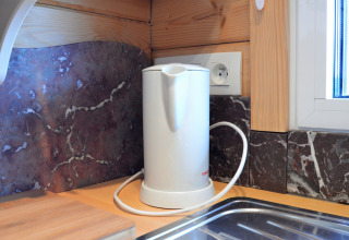 Bouilloire électrique sur le plan de travail au Chalet de Bioul en Belgique, devant un mur en marbre.