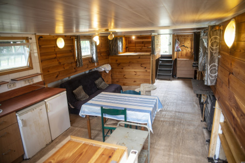 Knus houten interieur van woonboot 'Le Bateau du Lac Privé' in België met bank en eettafel.