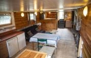 Accogliente interno in legno della houseboat 'Le Bateau du Lac Privé' in Belgio, con divano e tavolo.