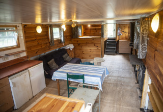 Knus houten interieur van woonboot 'Le Bateau du Lac Privé' in België met bank en eettafel.