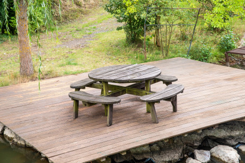 Ronde houten tafel met banken op een terras bij Le Bateau du Lac Privé, een woonboot in België.