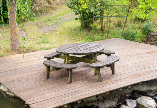 Ronde houten tafel met banken op een terras bij Le Bateau du Lac Privé, een woonboot in België.