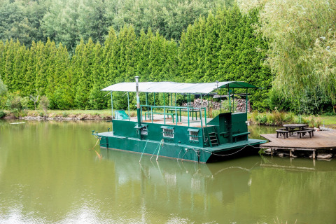 Groen woonboot Le Bateau du Lac Privé aangemeerd aan een rustige vijver met houten picknickterras.