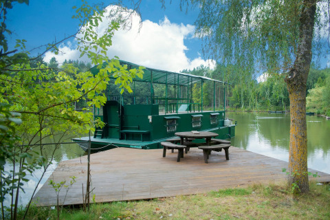 Woonboot 'Le Bateau du Lac Privé' aan een privémeer met houten terras en picknicktafel in België.