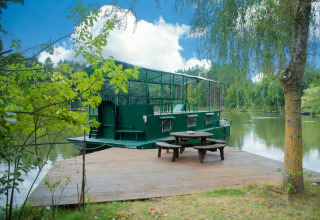 Woonboot 'Le Bateau du Lac Privé' aan een privémeer met houten terras en picknicktafel in België.