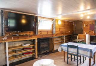 Woonruimte in woonboot 'Le Bateau du Lac Privé' in België, met eettafel en tv aan de muur.