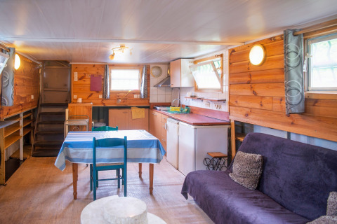 Interieur van woonboot Le Bateau du Lac Privé in België met keuken, eettafel en bank.